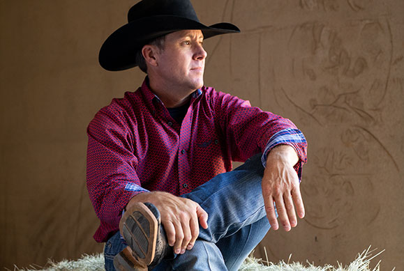 Trevor Brazile sitting on haystack